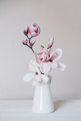 Beautiful fresh branches of magnolia flowers in full bloom in vase against white background....