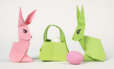 Easter origami bunnies and a basket of eggs on a white background. Paper crafts, do it yourself