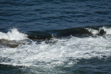 Aerial view looking down onto waves crashing onto rocks. North Berwick Scotland. 