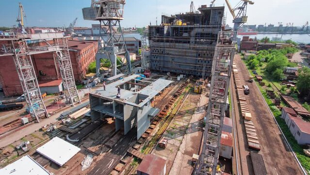 The construction of a large ship on a shipyard with cranes timelapse from above. A fragment of the case in the workshop of the plant. Metal frame during assembly