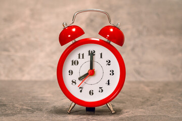 Red alarm clock on the grey stone background