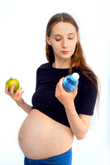 Pregnant woman propose apple for her belly copy space. Beautiful expectant lady having fresh snack, gray studio background. Healthy nutrition and pregnancy concept, copy space