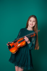 A girl in a green dress plays the violin on a plain green background.