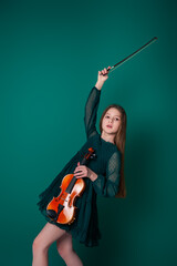 A girl in a green dress plays the violin on a plain green background.