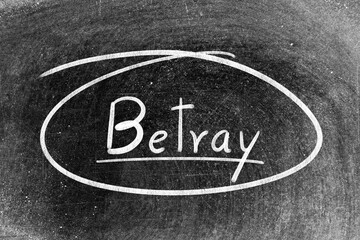White chalk hand writing in word betray and circle shape on blackboard background