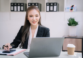 Business women calculate and analyzing graph document financial with laptop.