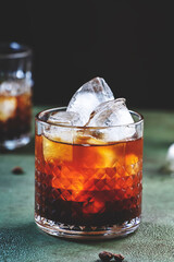 Black russian cocktail, alcoholic drink with vodka, coffee liqueur and ice, rusty green background, bar tools, copy space