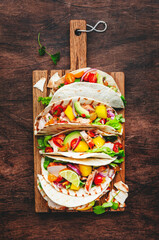 Tacos with grilled chicken, tomato salsa sauce, mango, cilantro and onion in corn tortilla on...