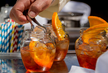 lano detalle de manos agregando hilo a un coctel aperitivo tipo spritz, con naranja en un frasco,...