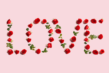 Creative layout with red roses, green leaves and Word LOVE. Love or Valentine's Day concept. Flat lay.