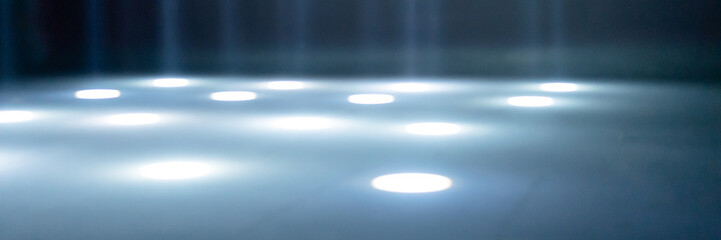 blurred rays of light on the disco floor. white blue neon searchlight lights. laser lines and lighting effect. night empty stage in studio with neon reflections. scene dark abstract background. banner