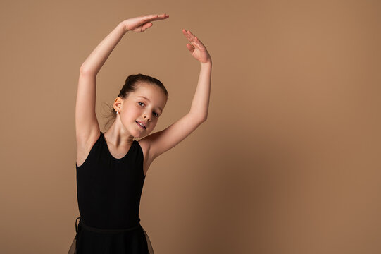 A girl in a gymnastic leotard performs ballet hand movements