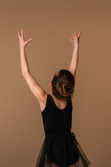 A girl in a hymantic black bodysuit with a ball in her hands. Beige background