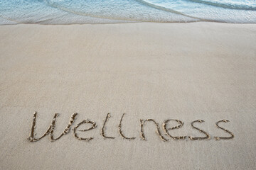 Wellness concept written on caribbean beach.