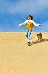 Pretty young girl playing with her young Border Collie in the dunes