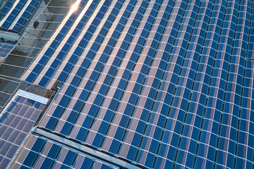 Aerial view of solar power plant with blue photovoltaic panels mounted on industrial building roof for producing green ecological electricity. Production of sustainable energy concept