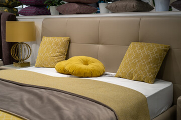 Decorative pillows on cozy bed with leather ocher colored headboard with gold brass lamp on bedside...