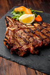 top view of delicious ribeye beef steak on the ribbon on the black stone plate with carrots slices