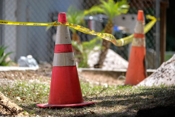 Yellow warning cones and tape as protective restriction barrier at industrial construction site. Safety for pedestrians