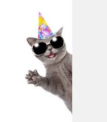 Happy cat wearing party's cap look from behind empty white banner and waved his paw. isolated on...