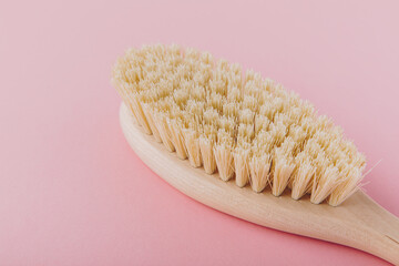 Massage brush. Natural wooden brush for body massage on pink background. Eco-friendly lifestyle...