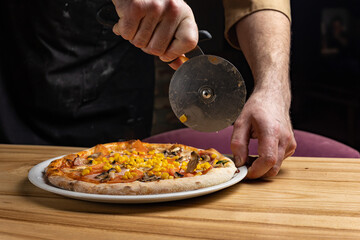 the chef prepares delicious pizza in the restaurant. Close-up
