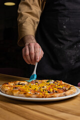 the chef prepares delicious pizza in the restaurant. Close-up

