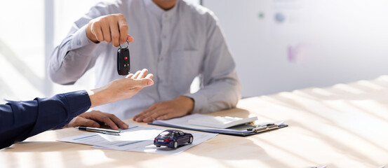 Car Insurance document or lease concept the car broker assisting his customer and explaining the...