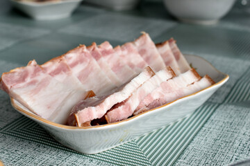 Sliced lard lies in rows on a porcelain plate.