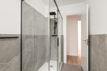 Bathroom with gray granite walls. The shower cabin is enclosed by glass transparent sliding doors...