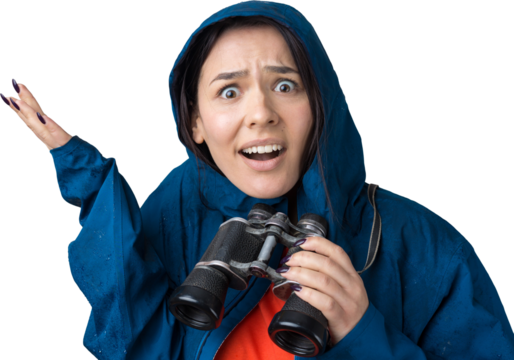 A tourist girl in a blue raincoat holds binoculars in her hands and looks into the distance, spies.