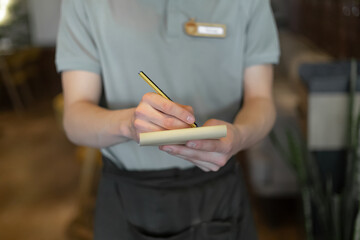 Waitress hand noting down menu on notebook in cafe.