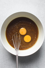 Eggs, Melted butter and brown sugar  in a white mixing bowl, process of making blondies