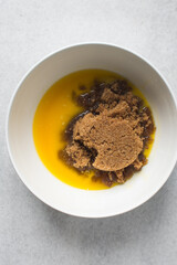 Melted butter and brown sugar in a white bowl, process of making blondies