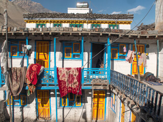Kagbeni, Annapurna Circuit, Nepal. Colourful house with aluminium water tank and rugs hanging to...