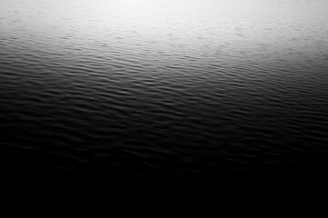 Dark black and gray blurred background has a little abstract light