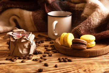 Sweet macaroons on wooden board with cup of coffee and a burning candle. Atmospheric photo. Content for social networks