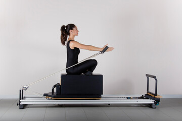pilates machine, young woman exercising in the gym