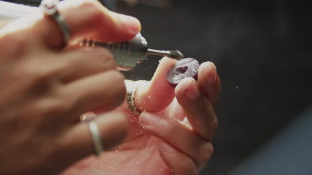 Hands of goldsmith drilling gemstone