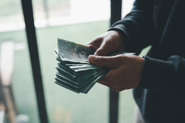 saving and payment concept, man holding bank note with blurred background vintage filter syle.