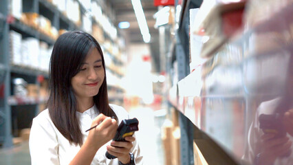 Female worker scanning products with barcode scanner in warehouse.