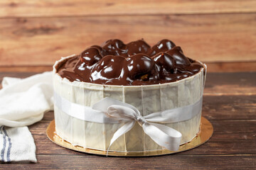 Profiterole cake. Cake with profiteroles surrounded by white chocolate on a wood background. close up