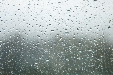 Raindrops on Window Glass Water Background Texture sky cloud at rainy day blur light gray rainy day