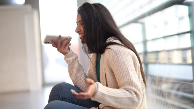 Young woman sitting in city talking on the phone