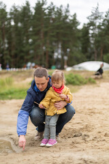 Fototapeta premium Little girl drawing on sand with her father