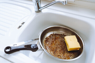Dirty burnt pan with leftover burnt food in kitchen sink