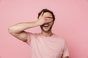 Fototapeta na wymiar Cheerful man covering his eyes with hand isolated over pink wall