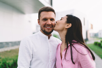 Cheerful multiethnic couple standing on street while smiling boyfriend looking at camera