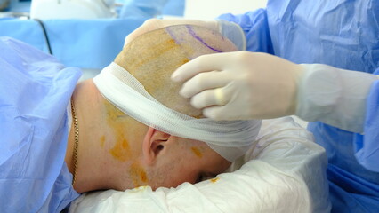 doctor operating on injured man.
doctor treating injured man