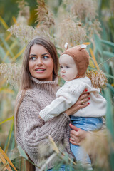 Obraz premium Beautiful young mother with her little daughter 2 years old in green park. Happy family. Cosy.